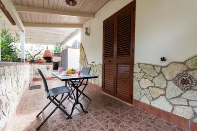 a patio with a table and chairs and a stone wall at Villa Caterina Scopello in Scopello