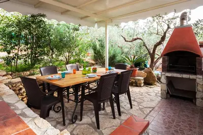 a patio with a table and a fireplace at Villa Caterina Scopello in Scopello