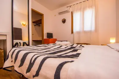 a large bed with a black and white striped blanket at B&B Le Dune - Self Check in in Lascari
