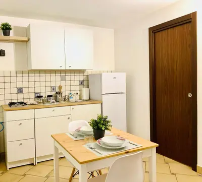 a kitchen with a wooden table and white cabinets at La Dimora della Cattedrale in Palermo
