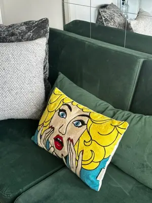 a pillow on a green couch with a painting of a woman at SuperAttico Bella Bellù in Palermo