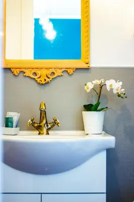 a sink with a mirror and a vase with flowers on it at SuperAttico Bella Bellù in Palermo