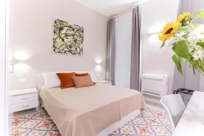 a white bedroom with a bed and a vase of flowers at Donna Isa B&B in Palermo