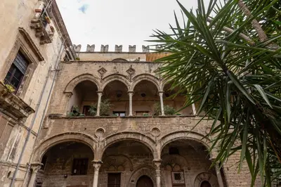 an old building with arches and a palm tree at Ajutamicristo Domus by DomuSicily in Palermo