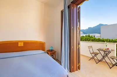 a bedroom with a bed and a balcony with a table at Hotel Sabbia d'Oro in San Vito lo Capo