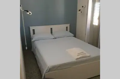 a bed with white sheets and pillows in a bedroom at Casa nel borgo marinaro di Santa Nicolicchia in Santa Flavia
