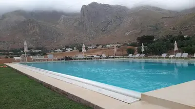 a large swimming pool with chairs and mountains in the background at stella di ponente in Macari