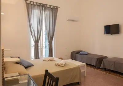 a room with two beds and a tv and a window at Piazza Florio Rooms in Palermo