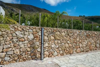 a stone retaining wall with a fence at Villa Mendez in Castellammare del Golfo
