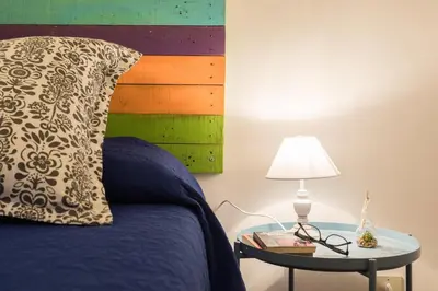 a bed with a pillow and a table with a lamp at Large apartment near Politeama 2 bathrooms Up to 8 Guests in Palermo