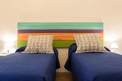 a bedroom with two beds and a wooden headboard at Large apartment near Politeama 2 bathrooms Up to 8 Guests in Palermo