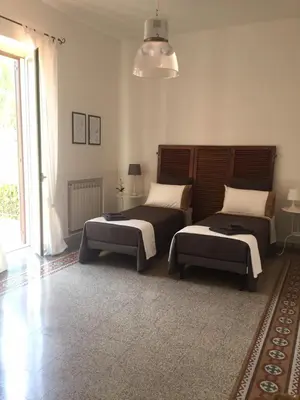 a bedroom with two beds and a large window at Villa la Rina in Palermo