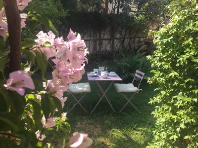 a table and chairs in a garden with pink flowers at Villa la Rina in Palermo
