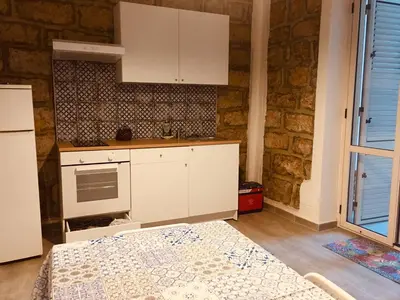 a kitchen with white cabinets and a bed in a room at Dost in Palermo