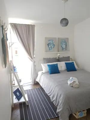 a bedroom with a bed with blue pillows and a ladder at Kalimera in Capaci