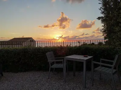 a table and two chairs with the sunset in the background at casa Cuffa in San Vito lo Capo