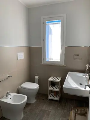 a bathroom with a toilet and a sink and a window at casa Cuffa in San Vito lo Capo