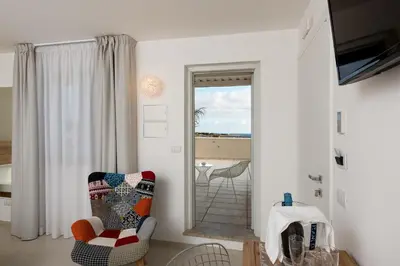 a living room with a chair and a view of the ocean at Artemide Hotel in San Vito lo Capo
