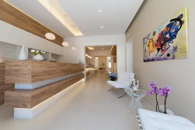 a living room with white furniture and a painting on the wall at Artemide Hotel in San Vito lo Capo