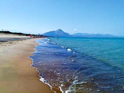 a beach with the ocean and mountains in the background at casa tre noci in Lascari