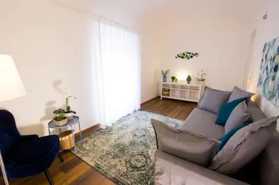 a living room with a gray couch and a blue chair at Casa MaMo 36 in Palermo