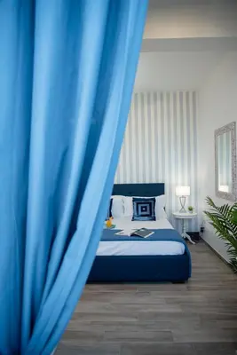 a bedroom with a bed with a blue curtain at Porta Aragonese Luxury Rooms in Palermo