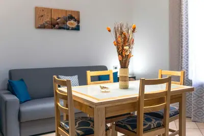 a dining room with a table and chairs and a couch at Perla di Mare Appartamenti in Castelluzzo