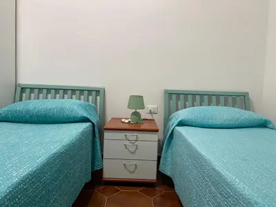 two beds with blue covers and a night stand with a lamp at La Casetta di Nonna Anna in Palermo