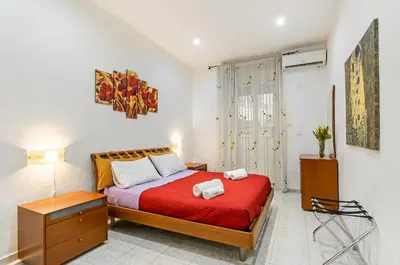 a bedroom with a bed with a red bedspread at GuestHost - Corso dei Mille Railway Apartment in Palermo