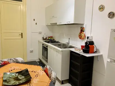 a kitchen with white cabinets and a sink and a table at Monfenera Apartment 3 in Palermo