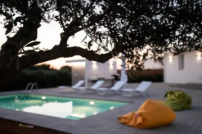 a swimming pool with lounge chairs and a tree at Villa Cappèddu in Balestrate