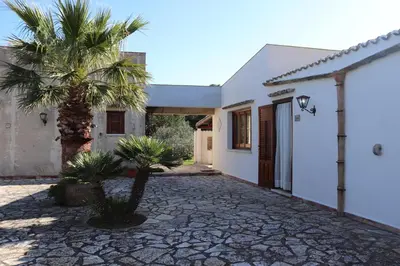 a palm tree in front of a house at Baglio Cracchiolo Casa Baldo in San Vito lo Capo