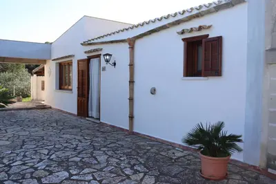 a white house with a potted plant in front of it at Baglio Cracchiolo Casa Baldo in San Vito lo Capo