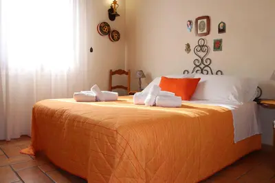a bedroom with a large bed with orange and white sheets at Baglio Cracchiolo Casa Baldo in San Vito lo Capo