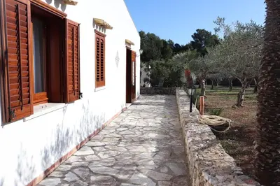 a stone walkway next to a white building at Baglio Cracchiolo Casa Baldo in San Vito lo Capo