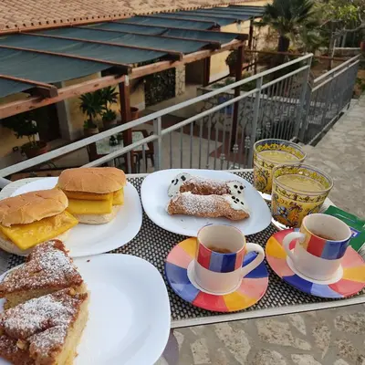 a table with plates of food and cups of coffee at Baglio Cracchiolo da Tuzzo - Casa Il Limone in San Vito lo Capo