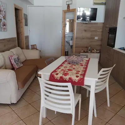 a kitchen and living room with a table and chairs at Baglio Cracchiolo da Tuzzo - Casa Il Limone in San Vito lo Capo