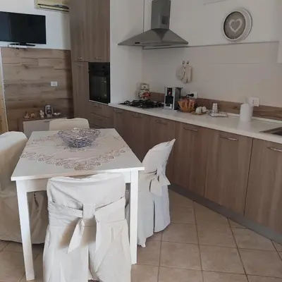 a kitchen with a white table with chairs and a sink at Baglio Cracchiolo da Tuzzo - Casa Il Limone in San Vito lo Capo