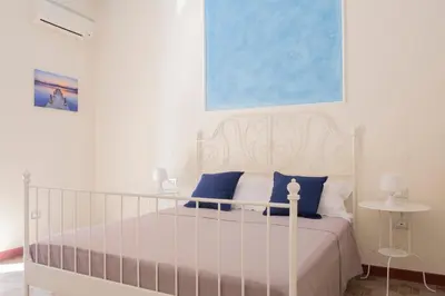 a bedroom with a white bed with blue pillows at Casa Gagliani, a Liberty house in the old downtown in Palermo