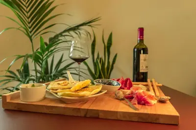 a wooden cutting board with food and a bottle of wine at Zefiro Suites in Palermo