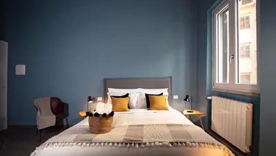 a blue bedroom with a bed with yellow pillows at Zefiro Suites in Palermo