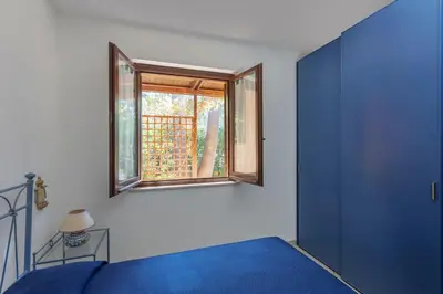 a bedroom with a blue bed and a window at VILLA GIAGGIA - VICINO IL MARE in San Vito lo Capo