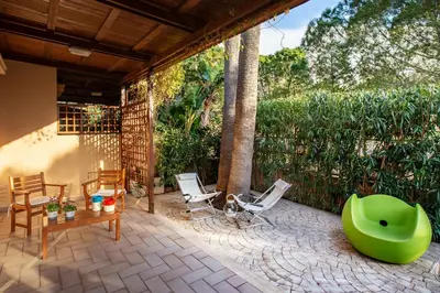 a patio with chairs and a green ottoman at VILLA GIAGGIA - VICINO IL MARE in San Vito lo Capo