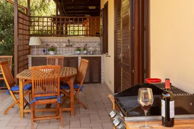 a patio with a table and chairs and a bottle of wine at VILLA GIAGGIA - VICINO IL MARE in San Vito lo Capo