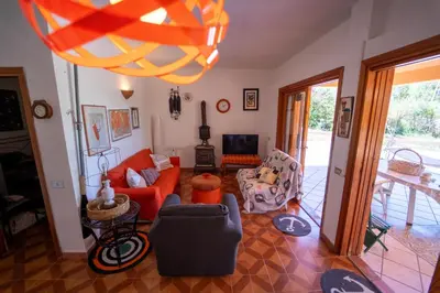 a living room with orange furniture and a large chandelier at Villa Claudia in Scopello