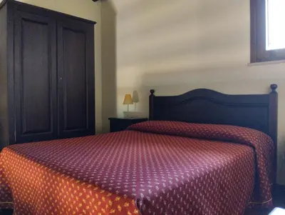 a bedroom with a large bed with an orange comforter at Agriturismo Masseria La Chiusa in San Giuseppe Jato