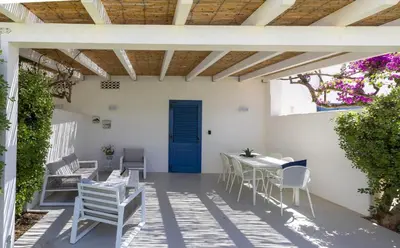 a patio with white chairs and tables and a blue door at Villa Turchese sul mare in San Vito lo Capo