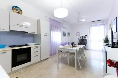 a kitchen with white cabinets and a table in it at Panorama del golfo in Balestrate
