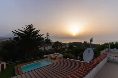 a sunset over a house with a swimming pool at Panorama del golfo in Balestrate