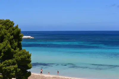 a group of people standing on a beach near the ocean at Villa Masetta - Luxury Suites in Mondello